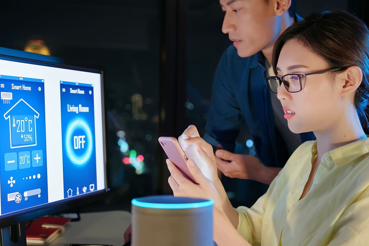 A man and a woman monitoring HVAC on a computer and phone