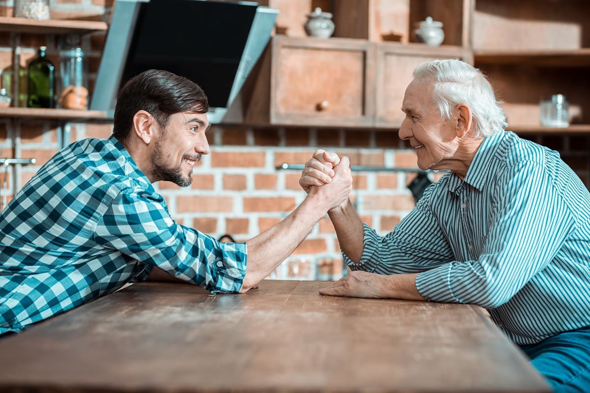 A young man and an older man arm wrestling