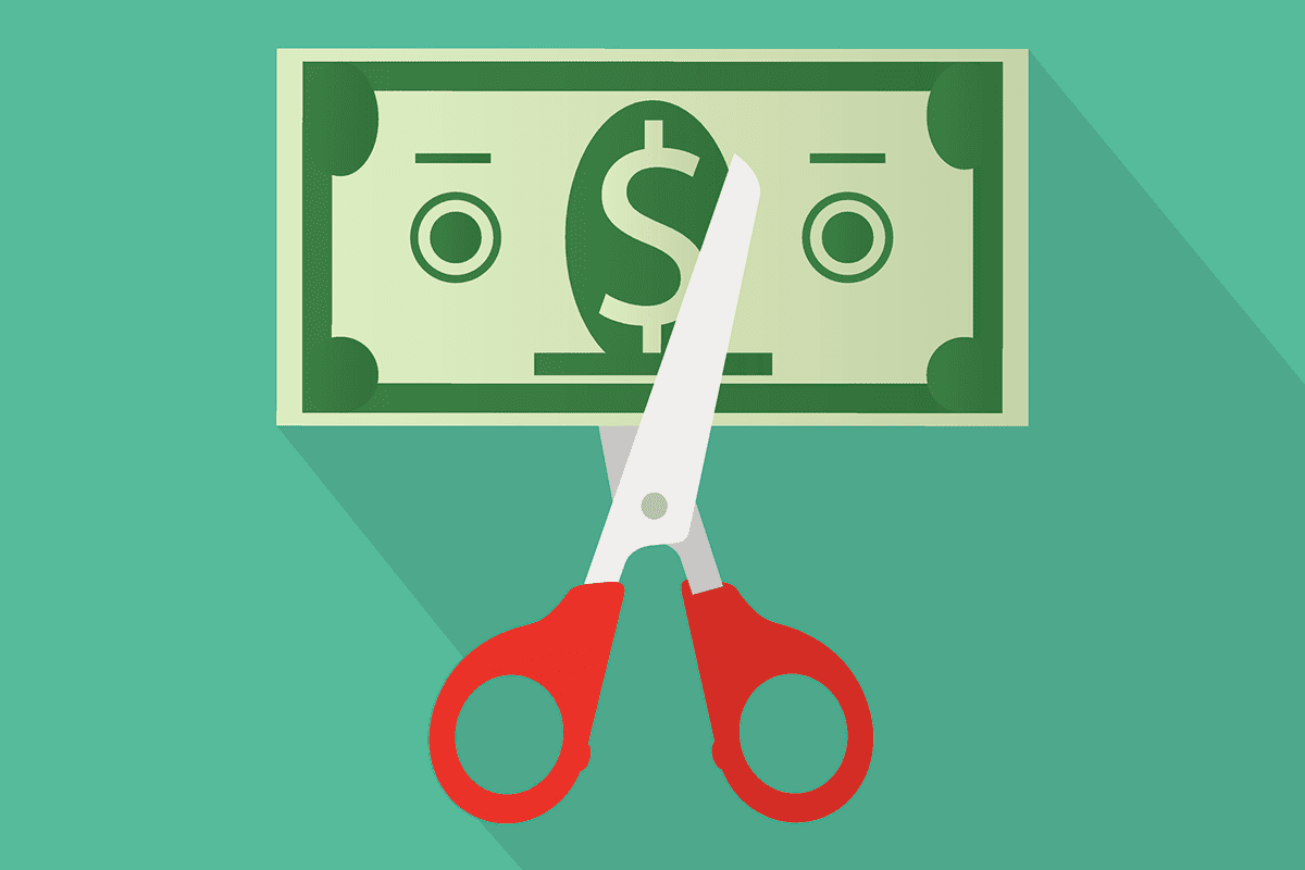 A pair of scissors cutting a dollar bill