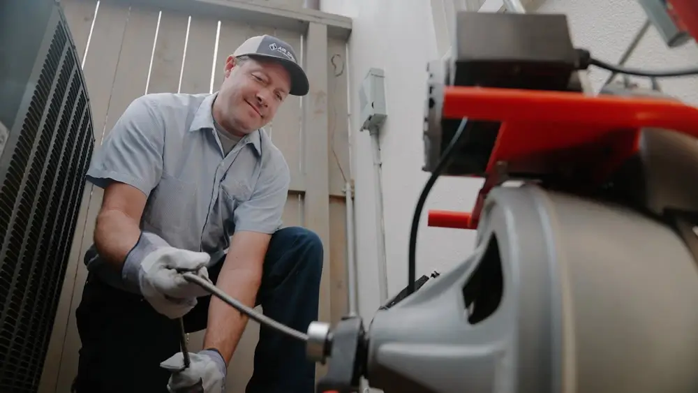 High Angle View Of Male Plumber Using Plunger In Bathroom Sink